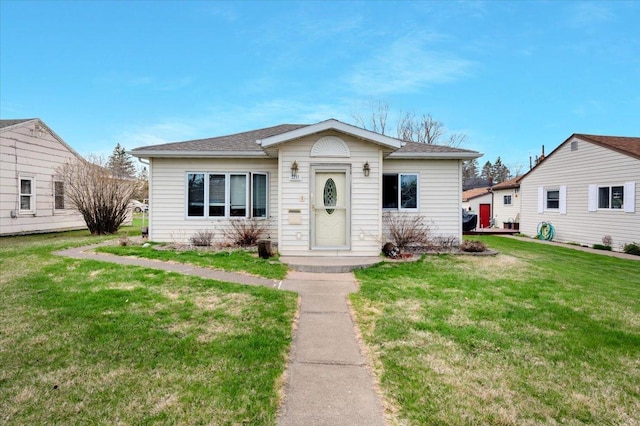bungalow featuring a front lawn and roof with shingles