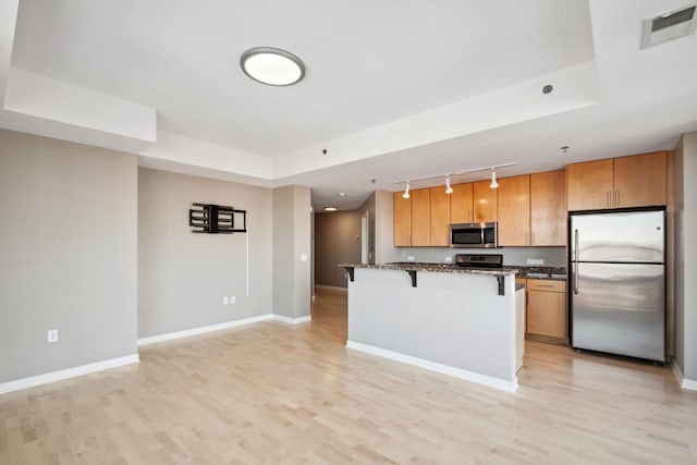 kitchen featuring stainless steel appliances, a kitchen bar, visible vents, and baseboards