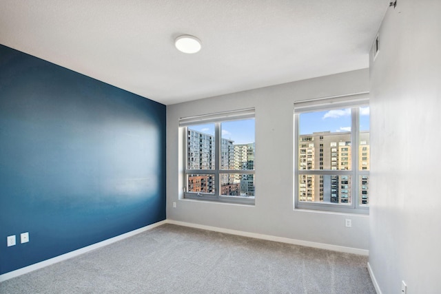 carpeted spare room featuring baseboards and a city view