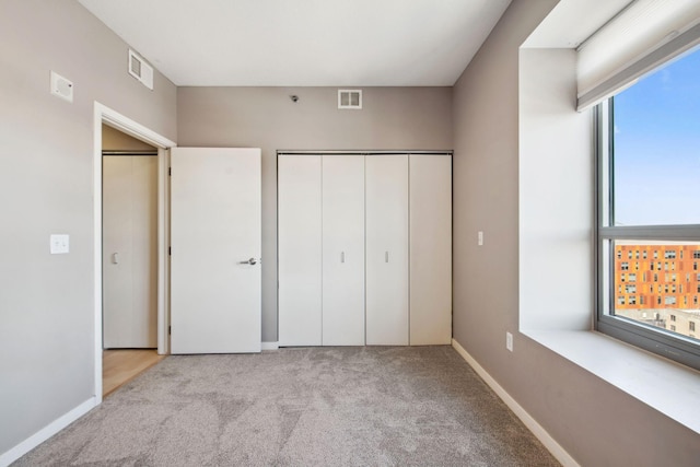 unfurnished bedroom featuring light carpet, a closet, visible vents, and baseboards