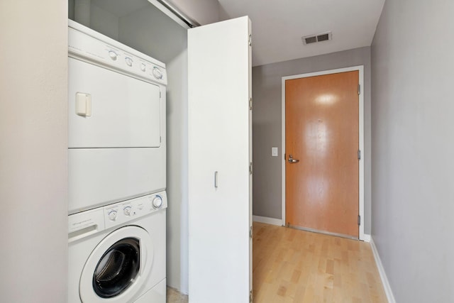 clothes washing area featuring laundry area, visible vents, baseboards, light wood-style floors, and stacked washer and clothes dryer