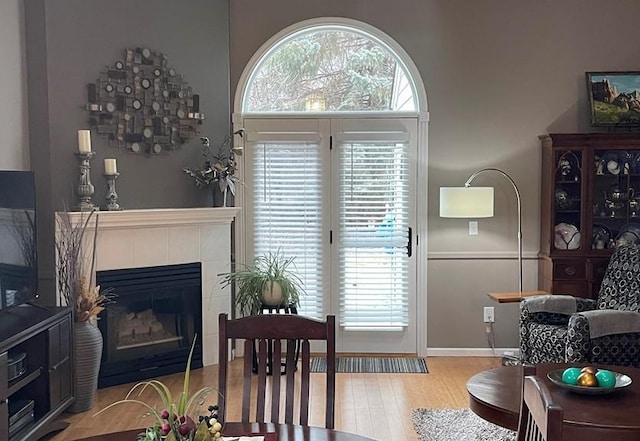 living room with a tiled fireplace, a wealth of natural light, and light hardwood / wood-style flooring