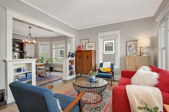 living area with ornamental molding, baseboards, an inviting chandelier, and wood finished floors