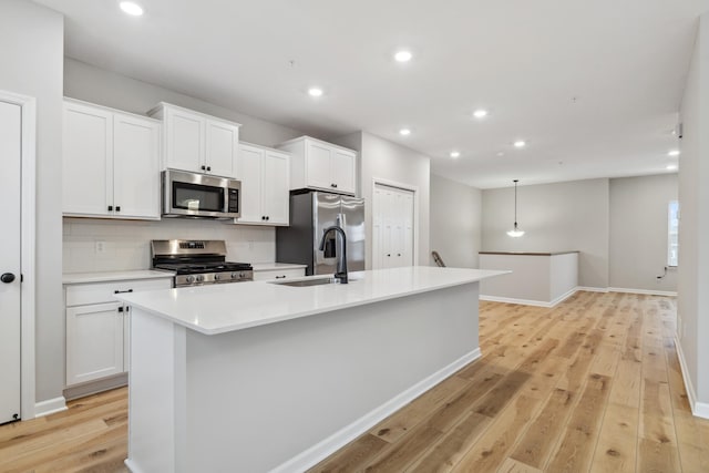 kitchen with sink, stainless steel appliances, an island with sink, and white cabinets