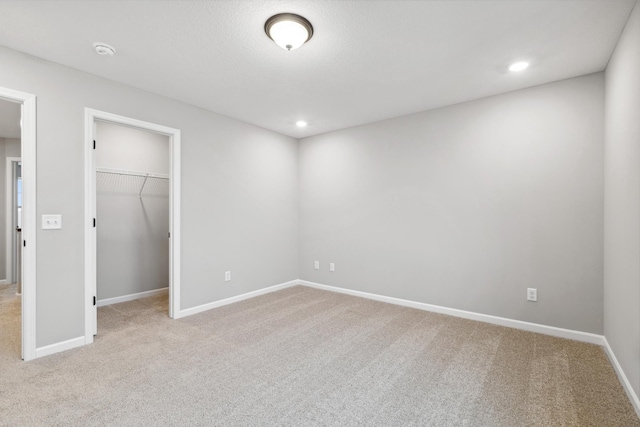 unfurnished bedroom with a walk in closet, light carpet, and a closet