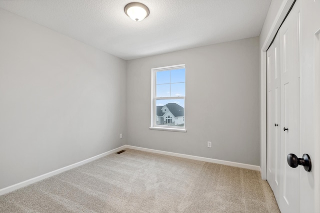 unfurnished bedroom with carpet floors, a closet, and a textured ceiling