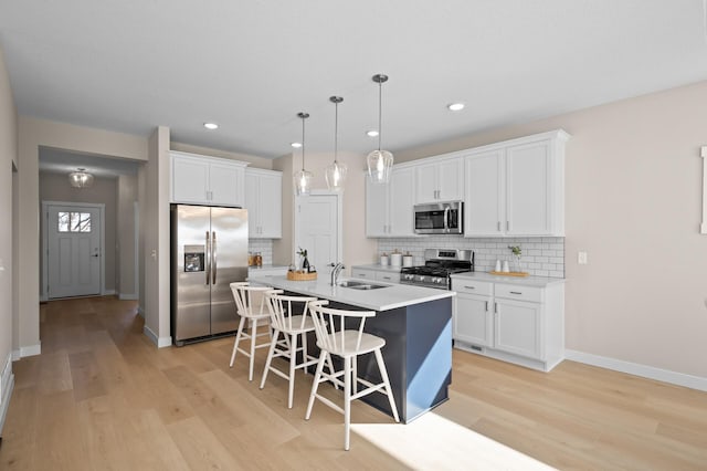 kitchen with white cabinetry, appliances with stainless steel finishes, a center island with sink, and pendant lighting