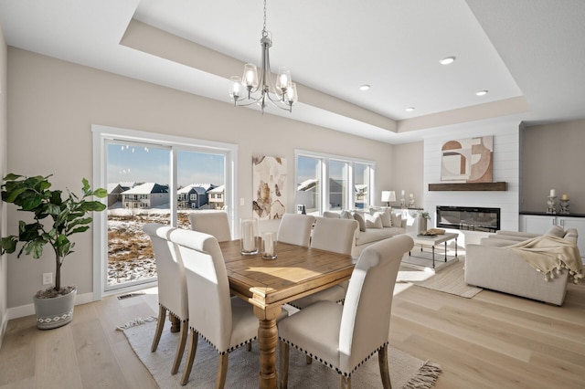 dining space featuring a large fireplace, a healthy amount of sunlight, and a raised ceiling