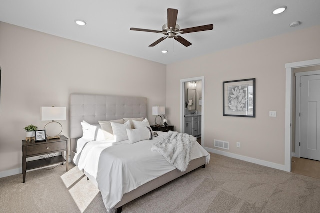 bedroom with ceiling fan, light colored carpet, and ensuite bathroom