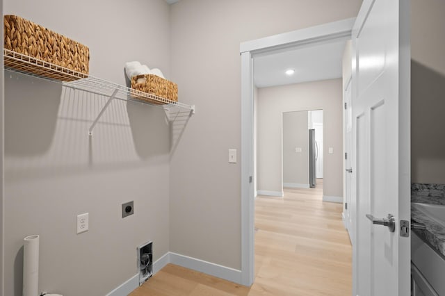 laundry room with hookup for an electric dryer and light wood-type flooring