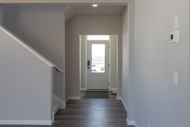 foyer entrance with dark wood-style floors, stairway, and baseboards