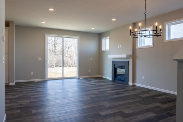 unfurnished living room with a glass covered fireplace, dark wood finished floors, baseboards, and recessed lighting