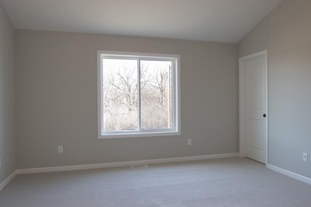 empty room with baseboards, visible vents, light colored carpet, and a healthy amount of sunlight