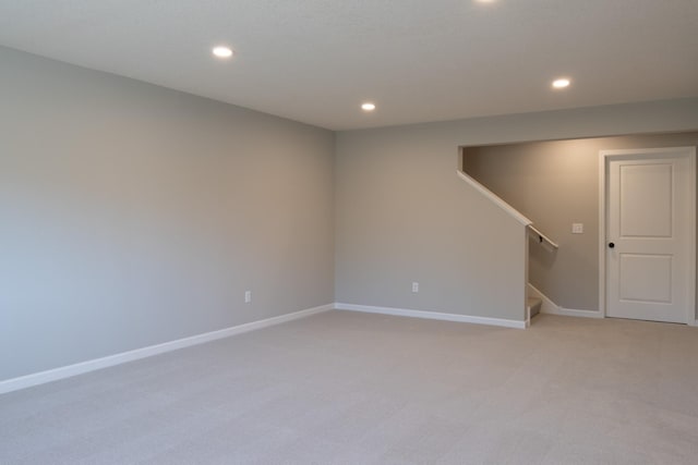 below grade area with light carpet, stairs, baseboards, and recessed lighting