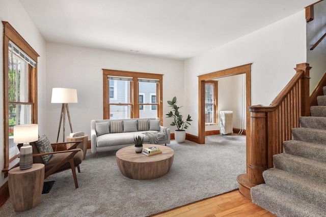 living room with visible vents, baseboards, light wood-type flooring, stairs, and radiator