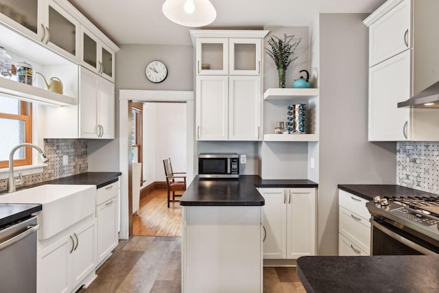 kitchen with dark countertops, appliances with stainless steel finishes, open shelves, and glass insert cabinets