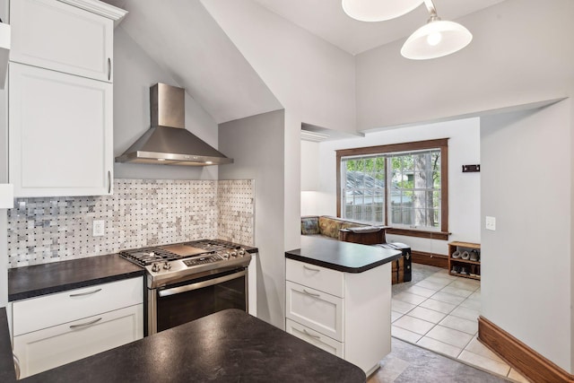 kitchen with white cabinetry, tasteful backsplash, stainless steel range with gas cooktop, dark countertops, and wall chimney range hood