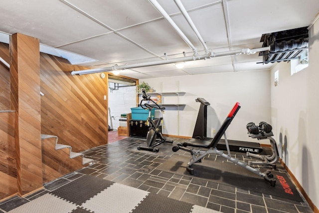 workout area featuring baseboards and wooden walls