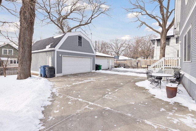 exterior space featuring a detached garage, fence, an outbuilding, and a gambrel roof