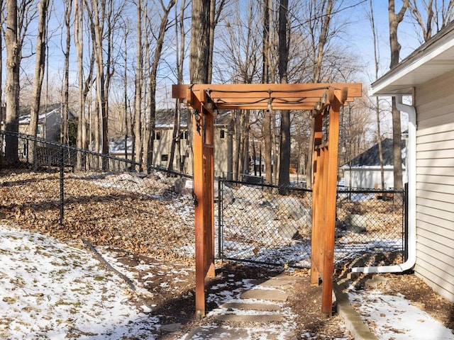 snowy yard featuring fence and a pergola