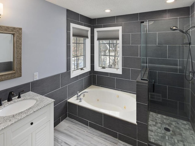 bathroom with a whirlpool tub, a shower stall, a textured ceiling, and vanity