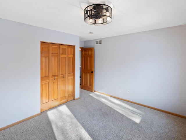 unfurnished bedroom featuring a closet, carpet flooring, visible vents, and baseboards