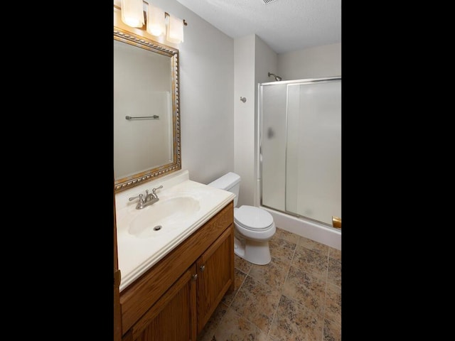 full bath with stone finish flooring, a shower stall, toilet, and vanity