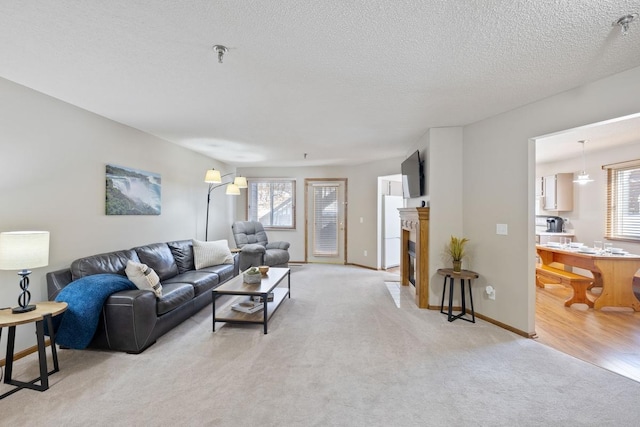 living room with a fireplace with flush hearth, a healthy amount of sunlight, light colored carpet, and a textured ceiling