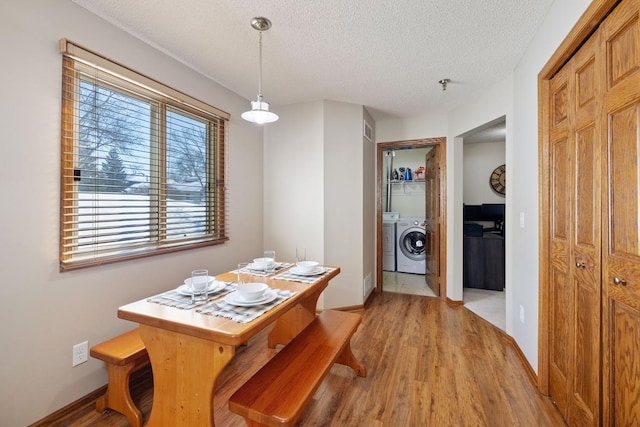 dining area featuring light wood-style floors, independent washer and dryer, a textured ceiling, and baseboards