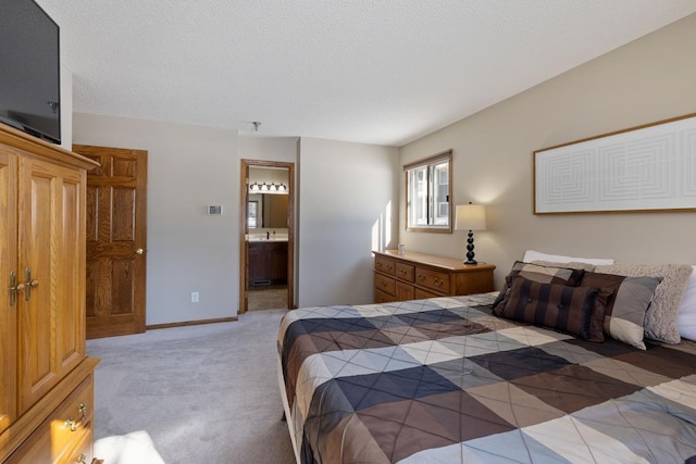 bedroom featuring a textured ceiling, carpet floors, connected bathroom, and baseboards