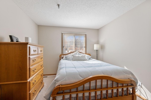 bedroom with baseboards, a textured ceiling, and light colored carpet