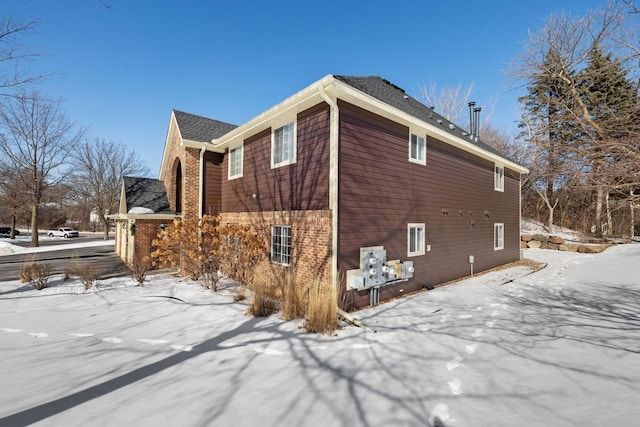 snow covered property with brick siding