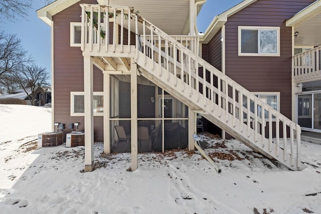 snow covered rear of property with stairs