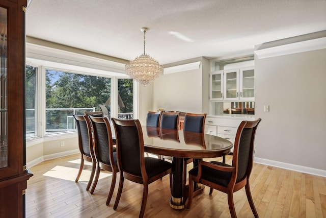 dining space with a textured ceiling, light hardwood / wood-style flooring, and a chandelier