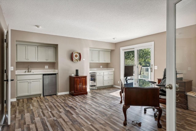 office area featuring dark wood-type flooring, indoor wet bar, wine cooler, and a textured ceiling