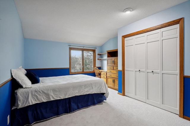 bedroom featuring a closet, lofted ceiling, and light carpet