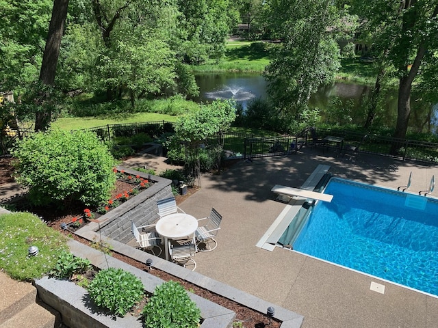 view of pool featuring a patio area, a diving board, and a water view