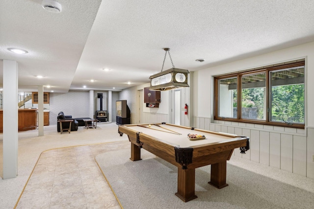 rec room featuring carpet floors, a wood stove, a textured ceiling, and billiards