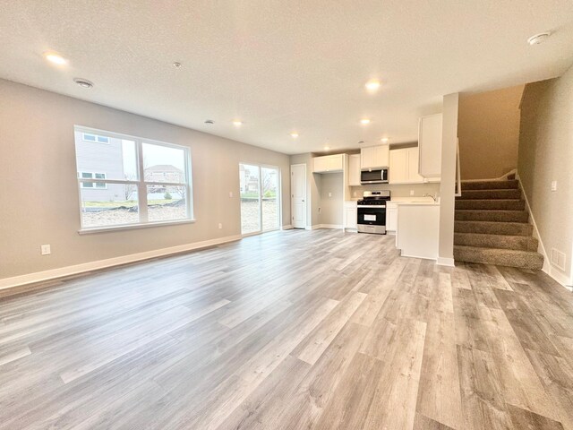 13643 Kaylemore Trl, Rosemount, MN 55068 - unfurnished living room featuring baseboards, recessed lighting, stairs, and light wood-style floors