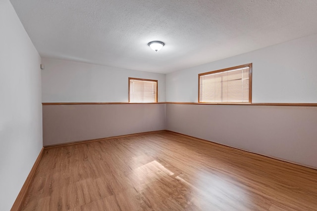 empty room with a textured ceiling and light wood-type flooring