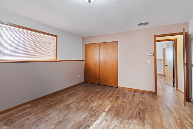 unfurnished bedroom featuring light hardwood / wood-style floors, a closet, and a textured ceiling