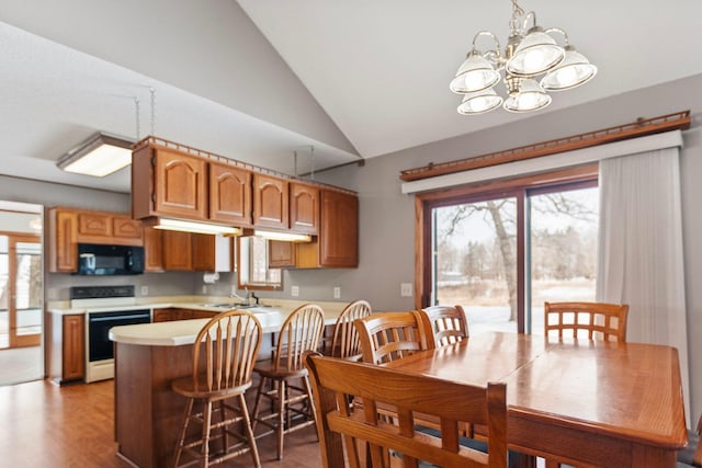 dining space featuring sink, vaulted ceiling, light hardwood / wood-style flooring, and a notable chandelier