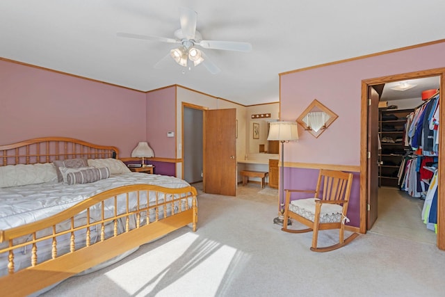 bedroom with ceiling fan, a walk in closet, ornamental molding, and light carpet