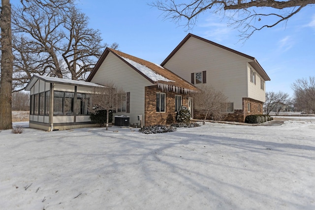 snow covered property featuring cooling unit and a sunroom