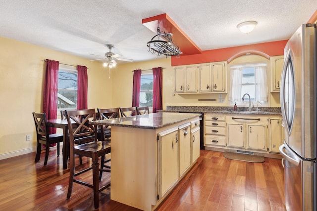 kitchen featuring sink, stainless steel refrigerator, hardwood / wood-style floors, a kitchen island, and cream cabinetry