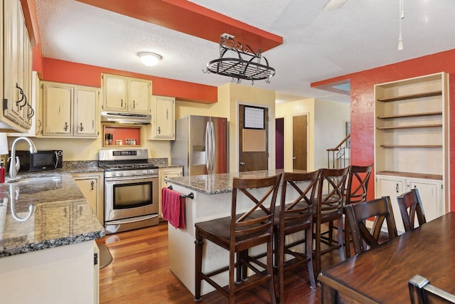 kitchen featuring stainless steel appliances, sink, a breakfast bar, and dark stone countertops