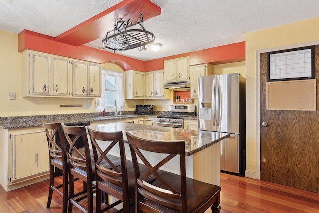 kitchen with sink, a center island, a textured ceiling, stainless steel appliances, and light hardwood / wood-style floors