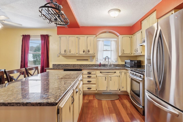 kitchen featuring a kitchen island, a wealth of natural light, sink, stainless steel appliances, and light wood-type flooring