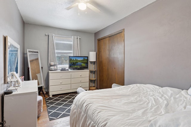 bedroom featuring ceiling fan, wood-type flooring, a closet, and a textured ceiling