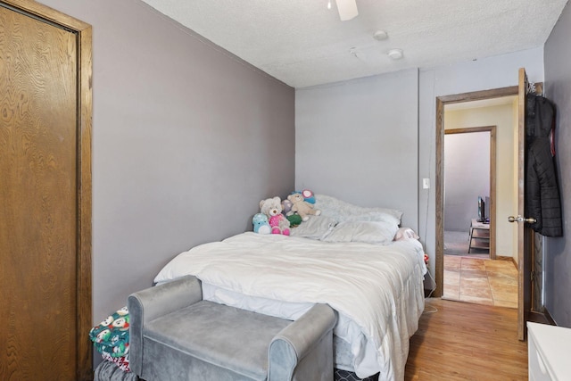 bedroom with ceiling fan, a textured ceiling, and light wood-type flooring